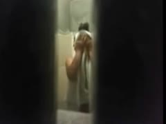 A slender brunette is shown drying herself off after having a shower in a spy cam footage.